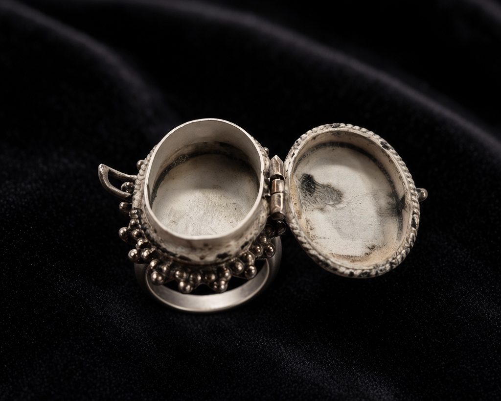 Sterling silver locket ring opened to show its hinged hidden compartment, on black velvet